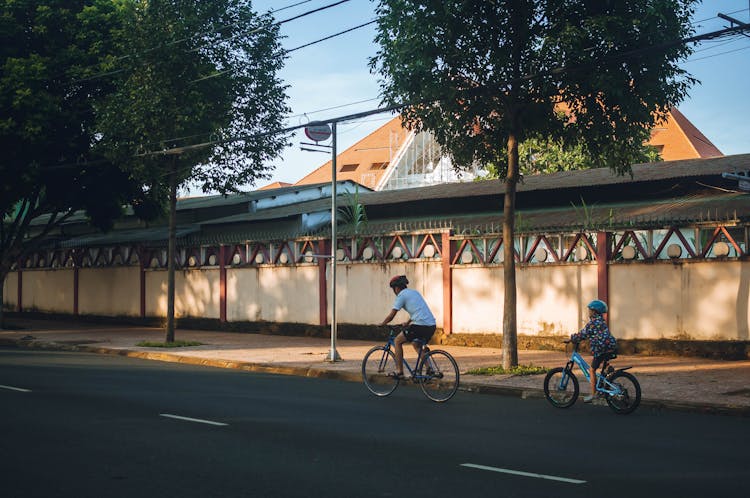 A Man Riding A Bike With His Child At The Back