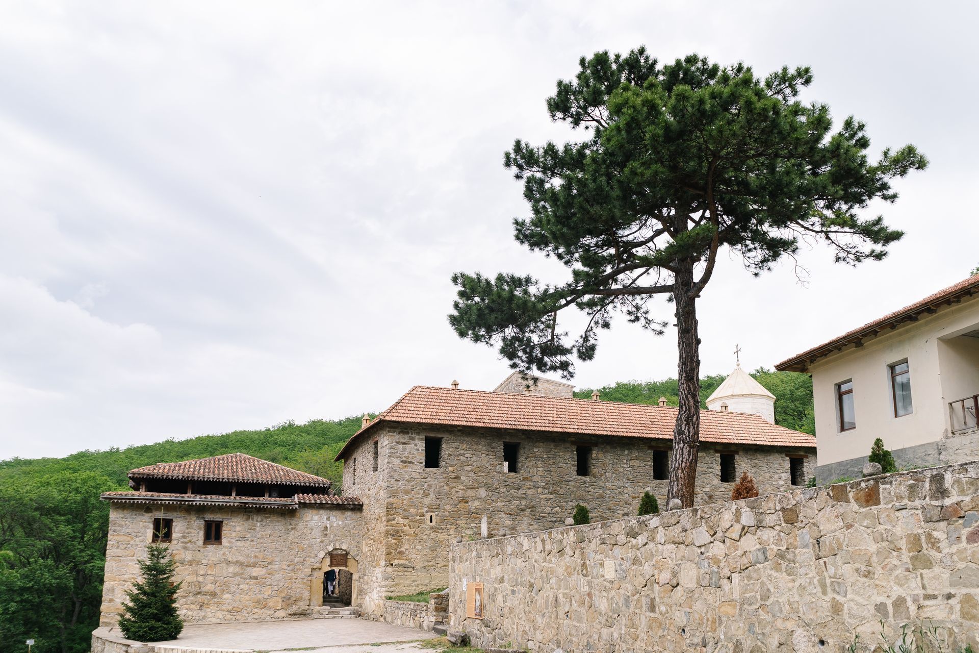 Scenic view of an ancient monastery with stone walls surrounded by lush greenery.