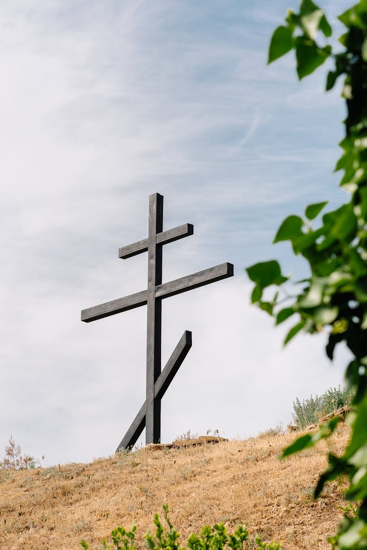 A Wooden Cross On A Grassy Field