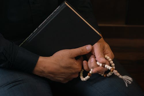 A Person Holding a Bible and a Rosary