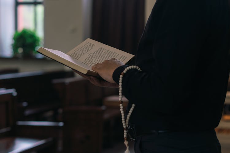 A Person In Black Long Sleeves Holding A Bible