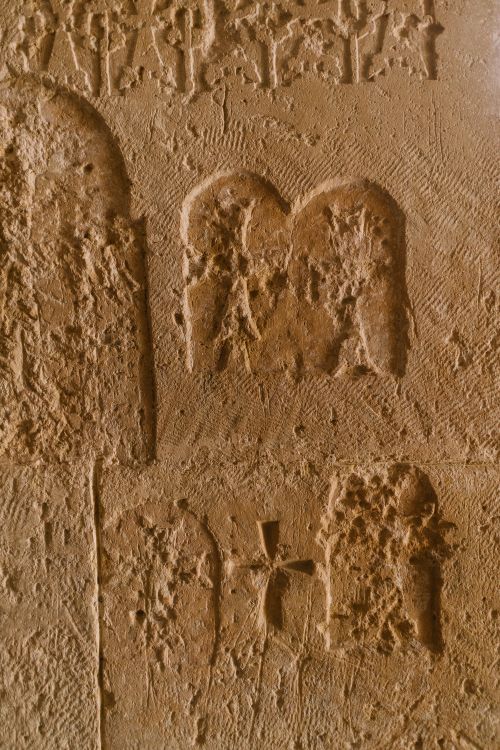 Free Detailed sandstone carvings depicting ancient symbols on a rough wall surface. Stock Photo