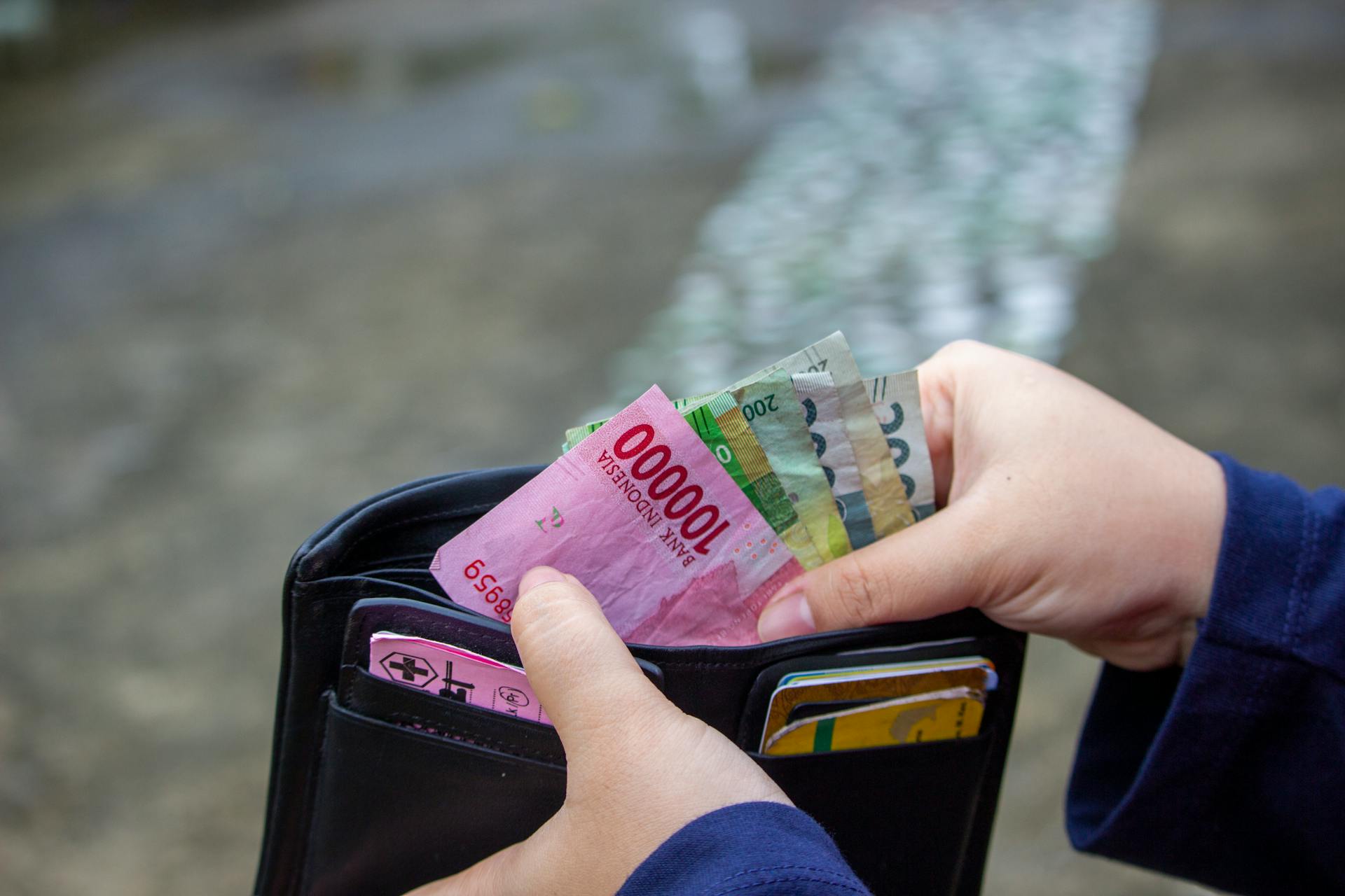 Close-up of hands managing banknotes, focusing on Indonesian Rupiah and diverse currencies