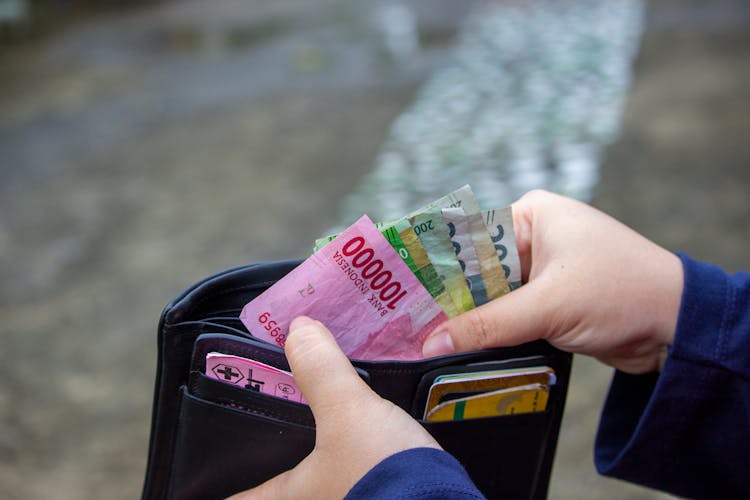 A Person Getting Money On A Wallet