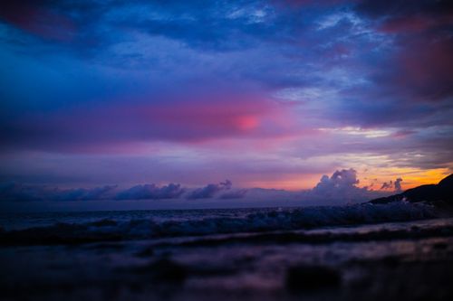 Free Stunning view of the ocean at sunset with vivid clouds and gently lapping waves. Stock Photo