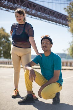 A duo showcasing modern street fashion under a Lisbon bridge in sunny Portugal.