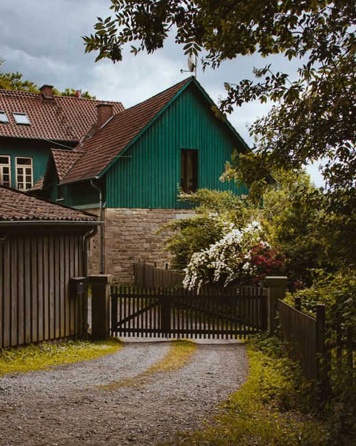 Picturesque rural house with vibrant garden and wooden gate.