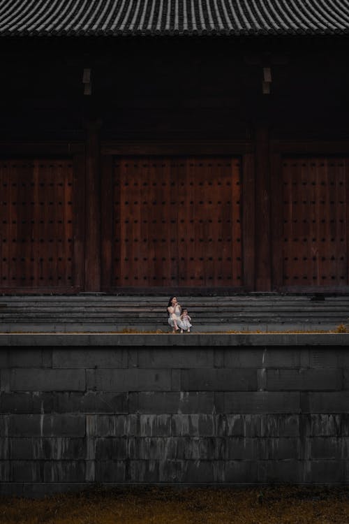 Free A Mother and Child Sitting Outside a Temple Stock Photo