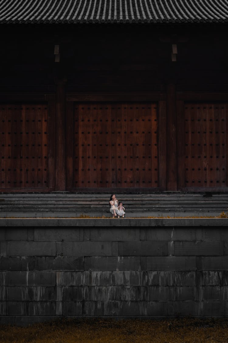 A Mother And Child Sitting Outside A Temple