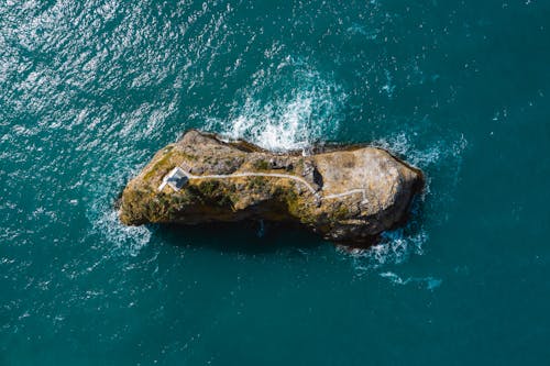 Top View of a Stone Island with a Building Surrounded by Blue Water 