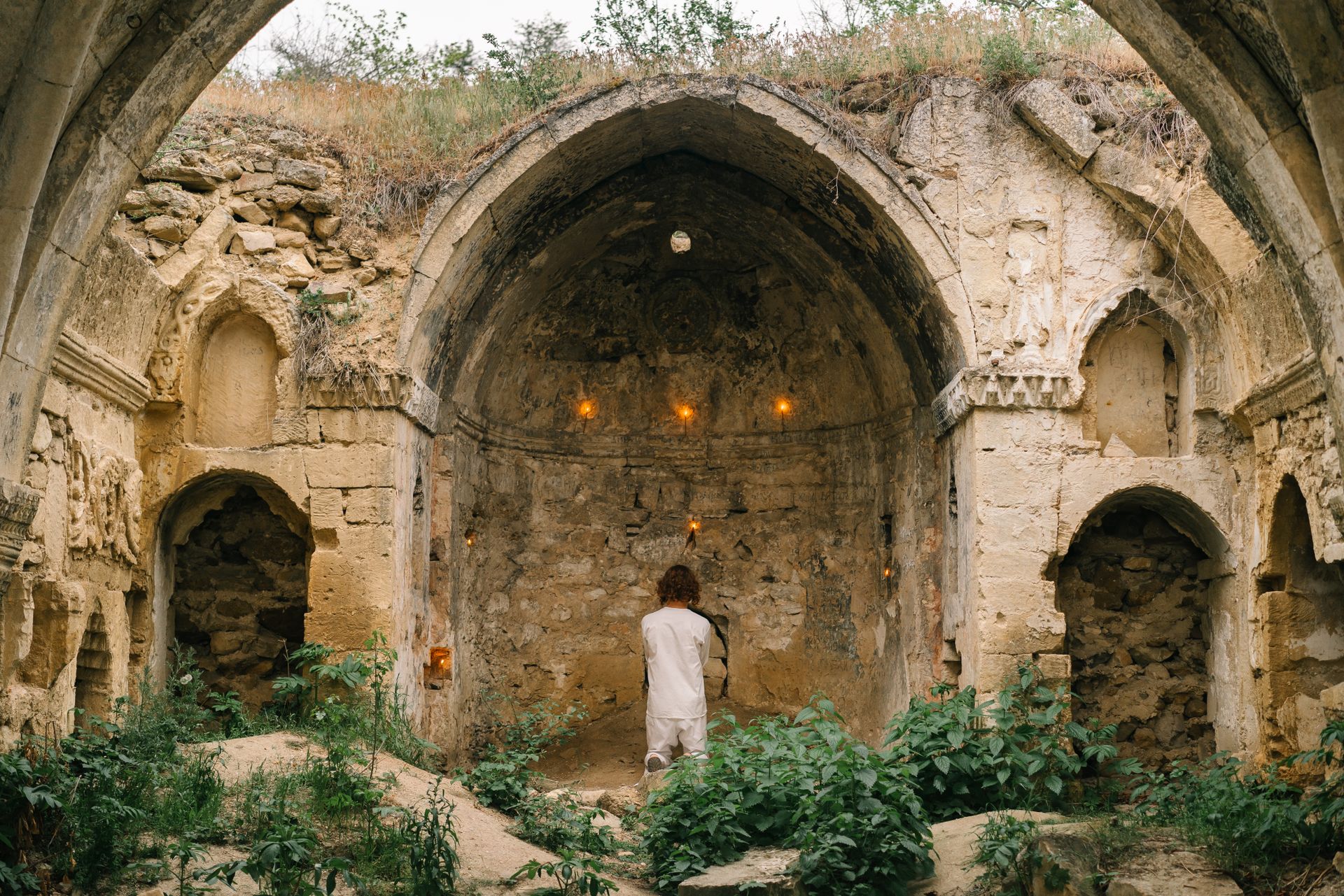 Person Kneeling in Prayer Outside Medieval Ruins Stone Church