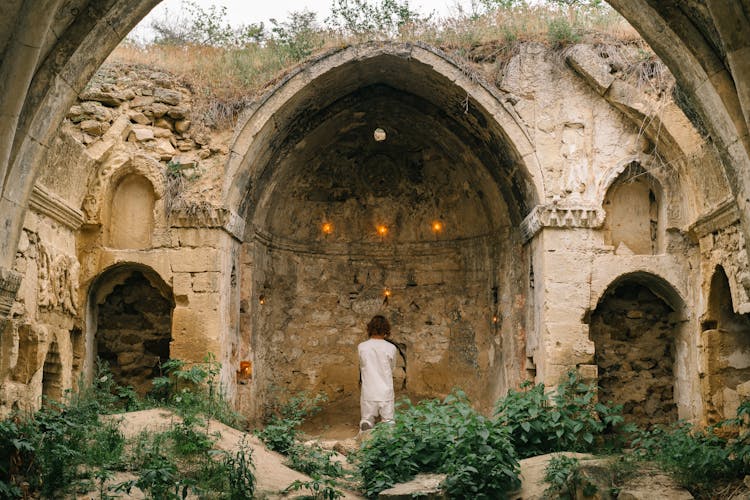 Person Kneeling In Prayer Outside Medieval Ruins Stone Church