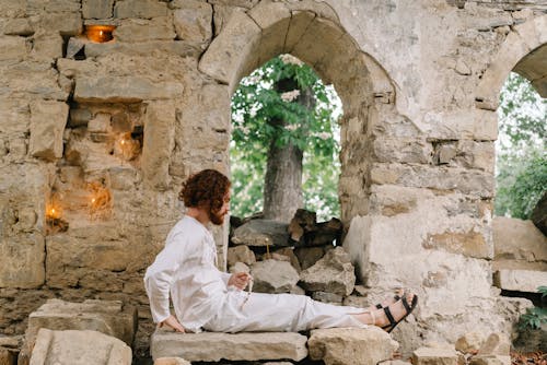 Man Sitting on Stones of Destroyed Church