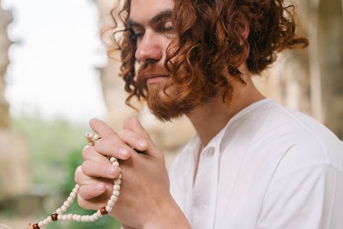 Close-Up Photo of a Man with Praying Hands and Prayer Beads