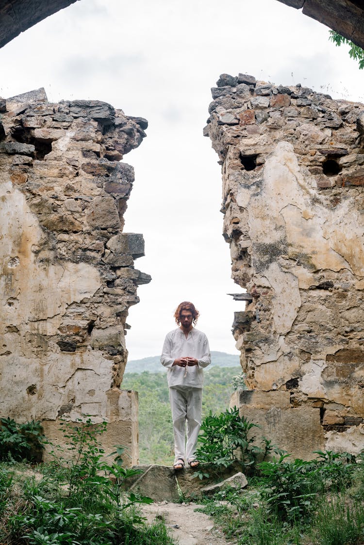 Man In White Clothing Standing In Ruins Of A Building 