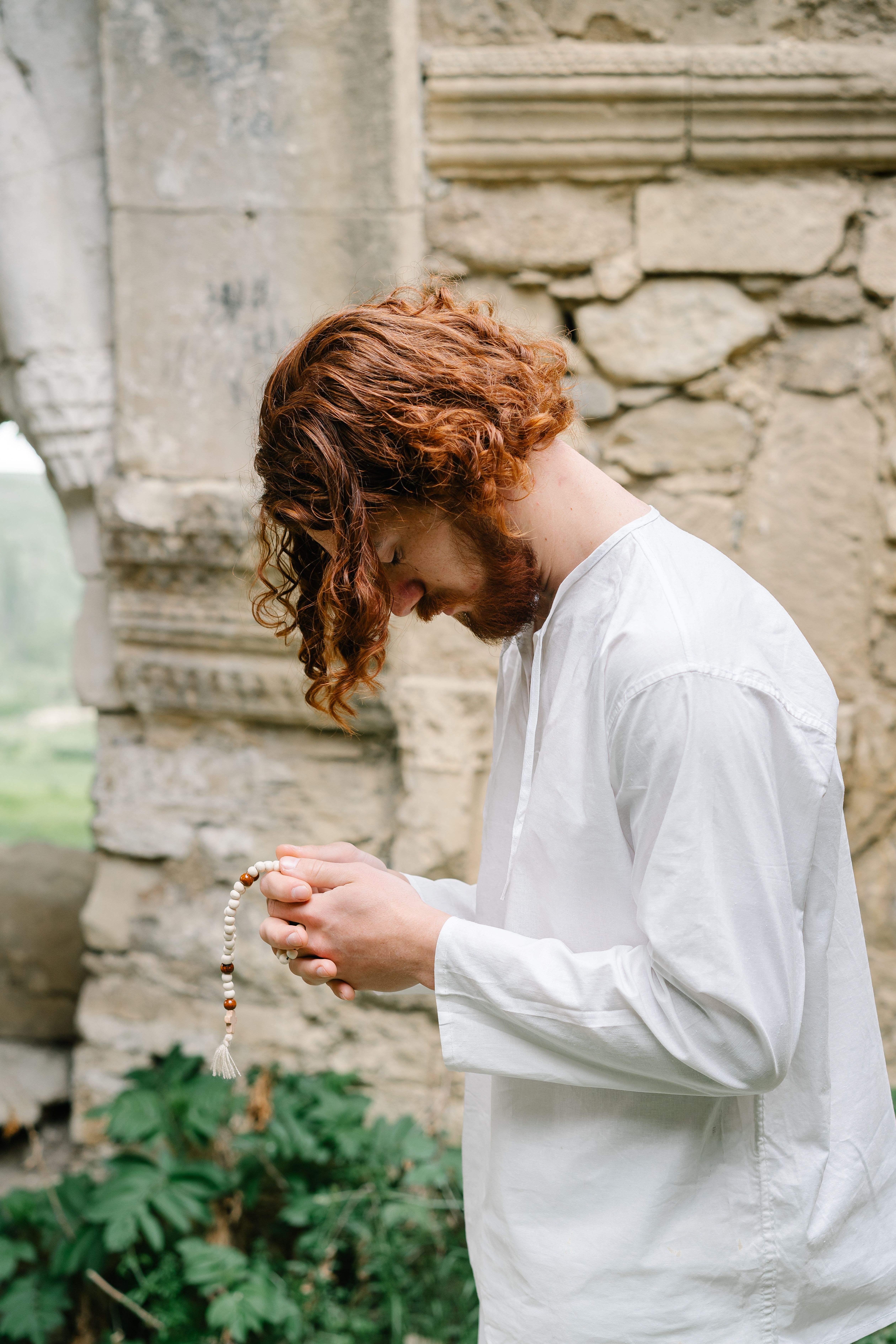 Man praying with a rosary in his hands outdoors