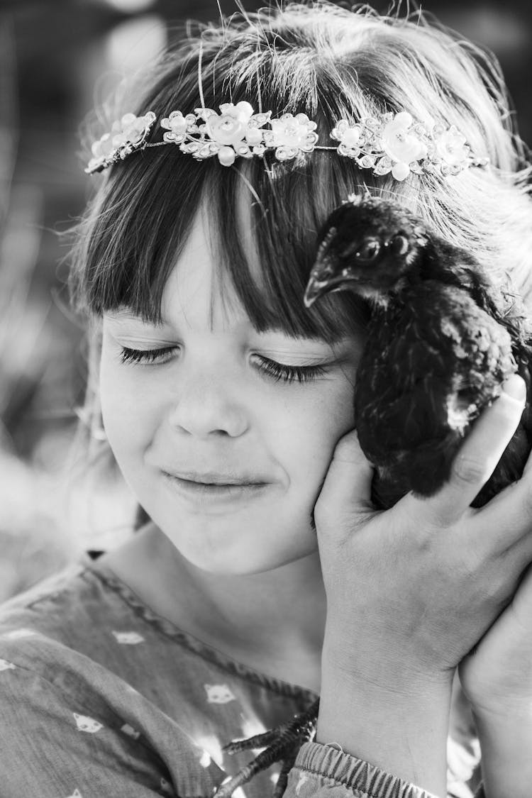 Grayscale Photo Of A Girl Holding Bird Near Face