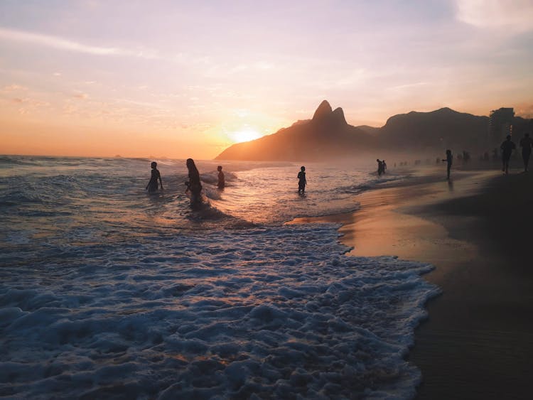 A Silhouette Of People On The Beach During Sunset