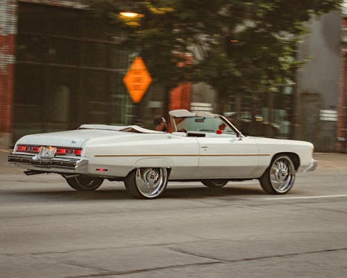 A White Vintage Car Moving on the Road