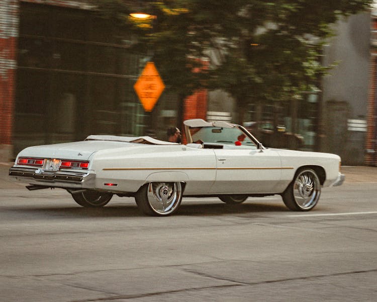 A White Vintage Car Moving On The Road