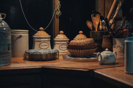 Cozy kitchen scene featuring wooden utensils, a teapot, and storage jars with warm lighting.