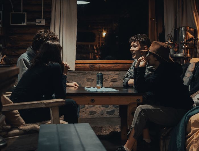 Four people talking in a rustic room, photo by Gaspar Zaldo on Pexels