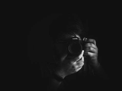 Free A dramatic black and white portrait of a photographer capturing a moment with a camera. Stock Photo