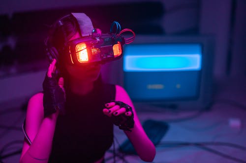 Woman Wearing Illuminated Goggles in a Room with Computer and Cables in the Background 