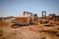 A tent set amidst ancient ruins in Idlib, Syria, reflecting a blend of history and modernity.