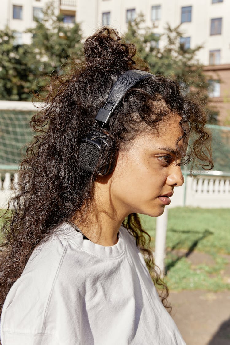 Side View Of A Young Woman Wearing Headphones And Standing Outside 