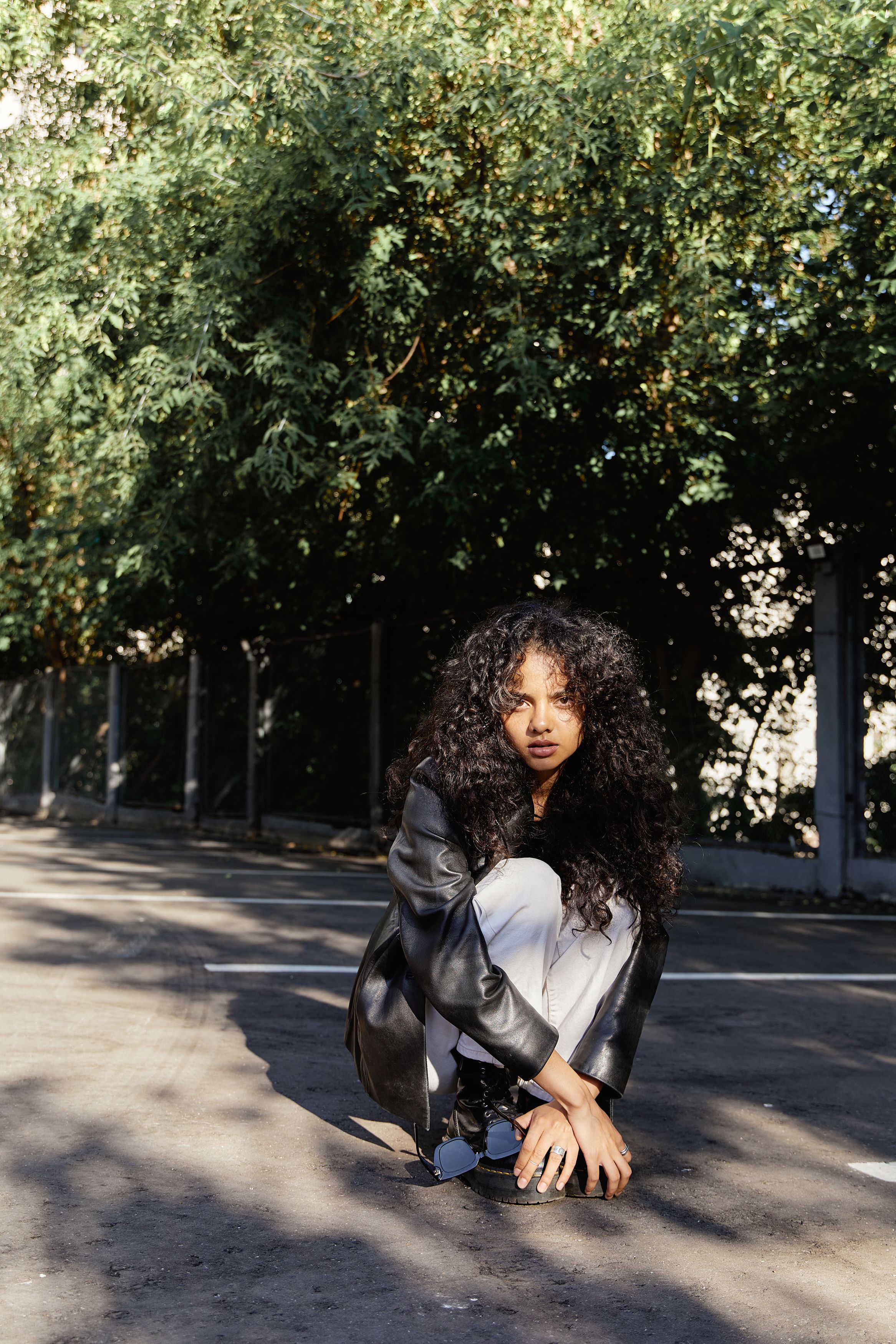 Woman in Black Leather Jacket and Denim Pants Sitting on Concrete ...