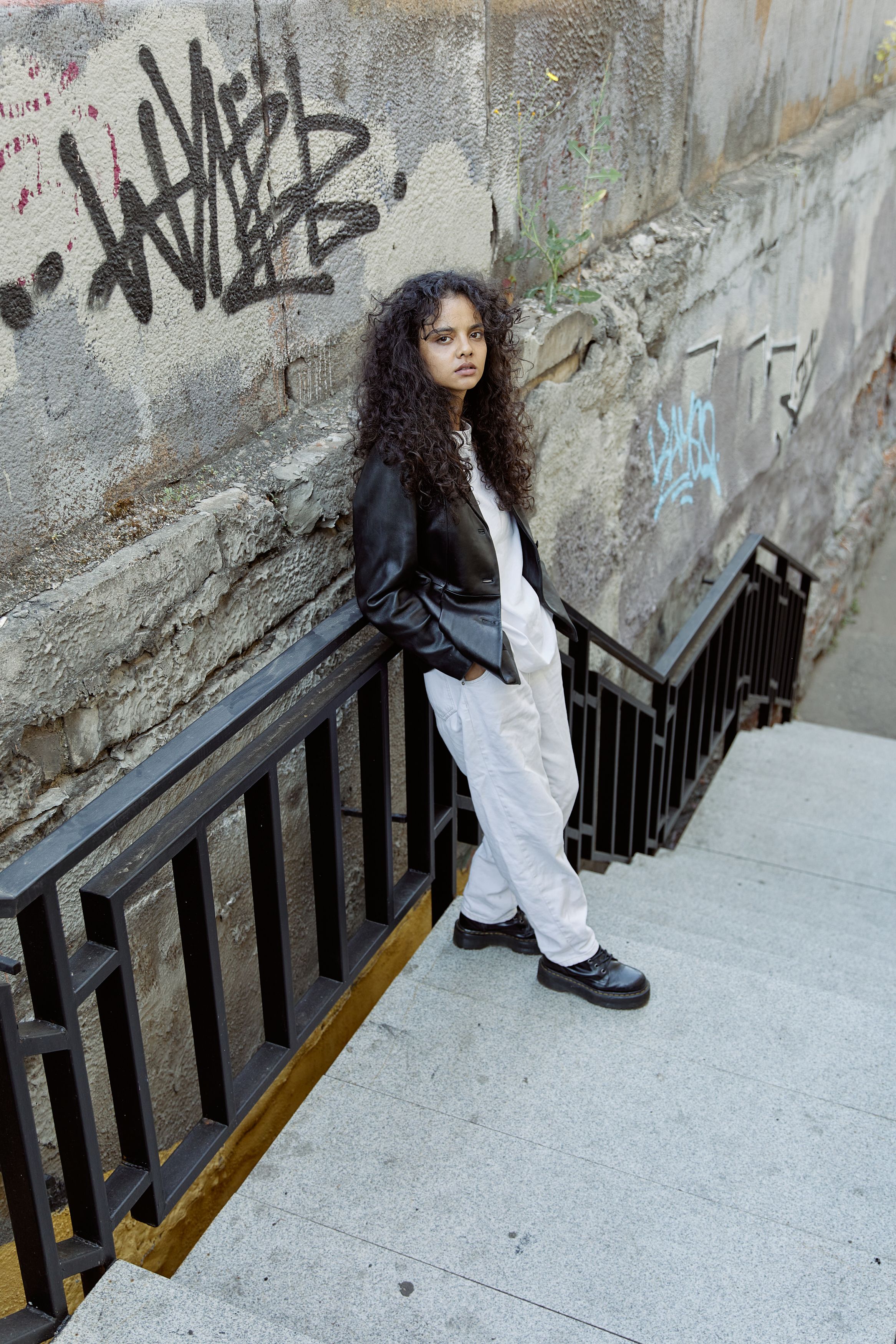 A Woman in Black Leather Jacket Standing on the Stairs · Free Stock Photo