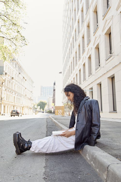 A Woman Reading a Book in on the Sidewalk