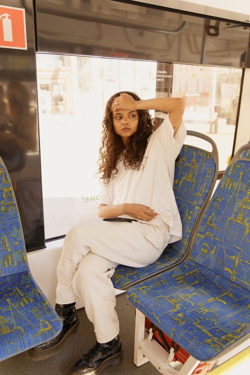 Free A young woman posing on a city bus, dressed in white and embracing urban life. Stock Photo