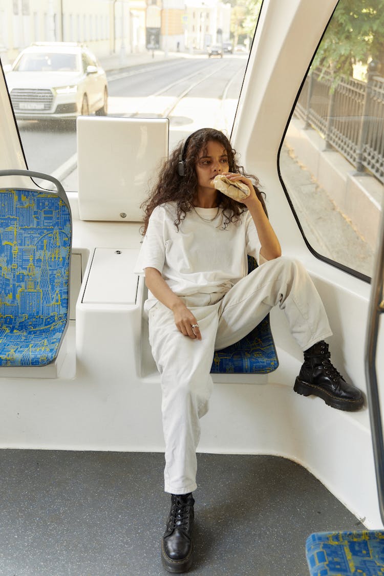 A Girl Eating Bread Sitting Alone In A Tram