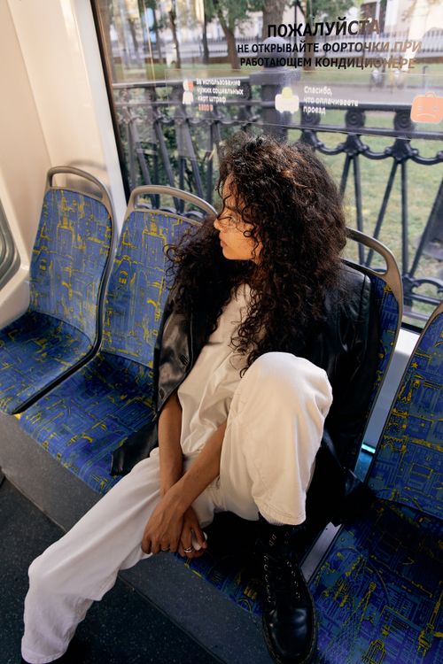 Free Woman in black leather jacket sits alone in a tram, lost in thought. Stock Photo