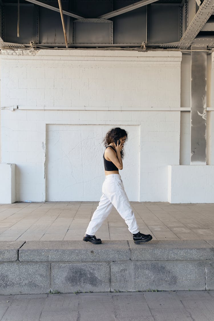 Woman Walking On A Concrete Platform Using A Smartphone