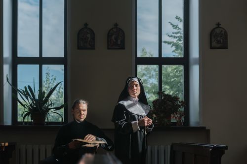 Free Nun and priest in a church, sunlight through windows enhances spirituality. Stock Photo
