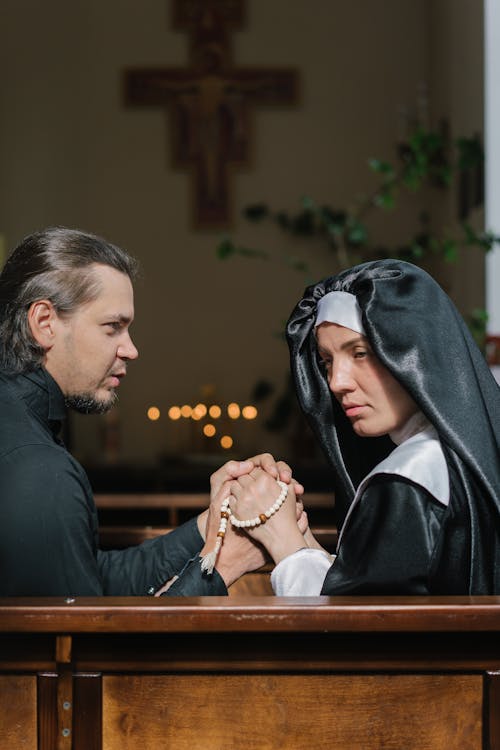 A Man Holding the Hands of a Woman with a Rosary Wearing a Black Veil 
