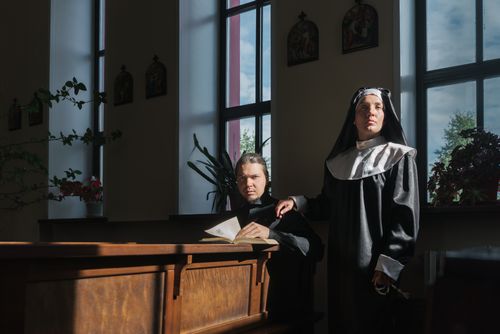 Free A nun and priest in a church setting with natural light through windows, conveying a religious atmosphere. Stock Photo
