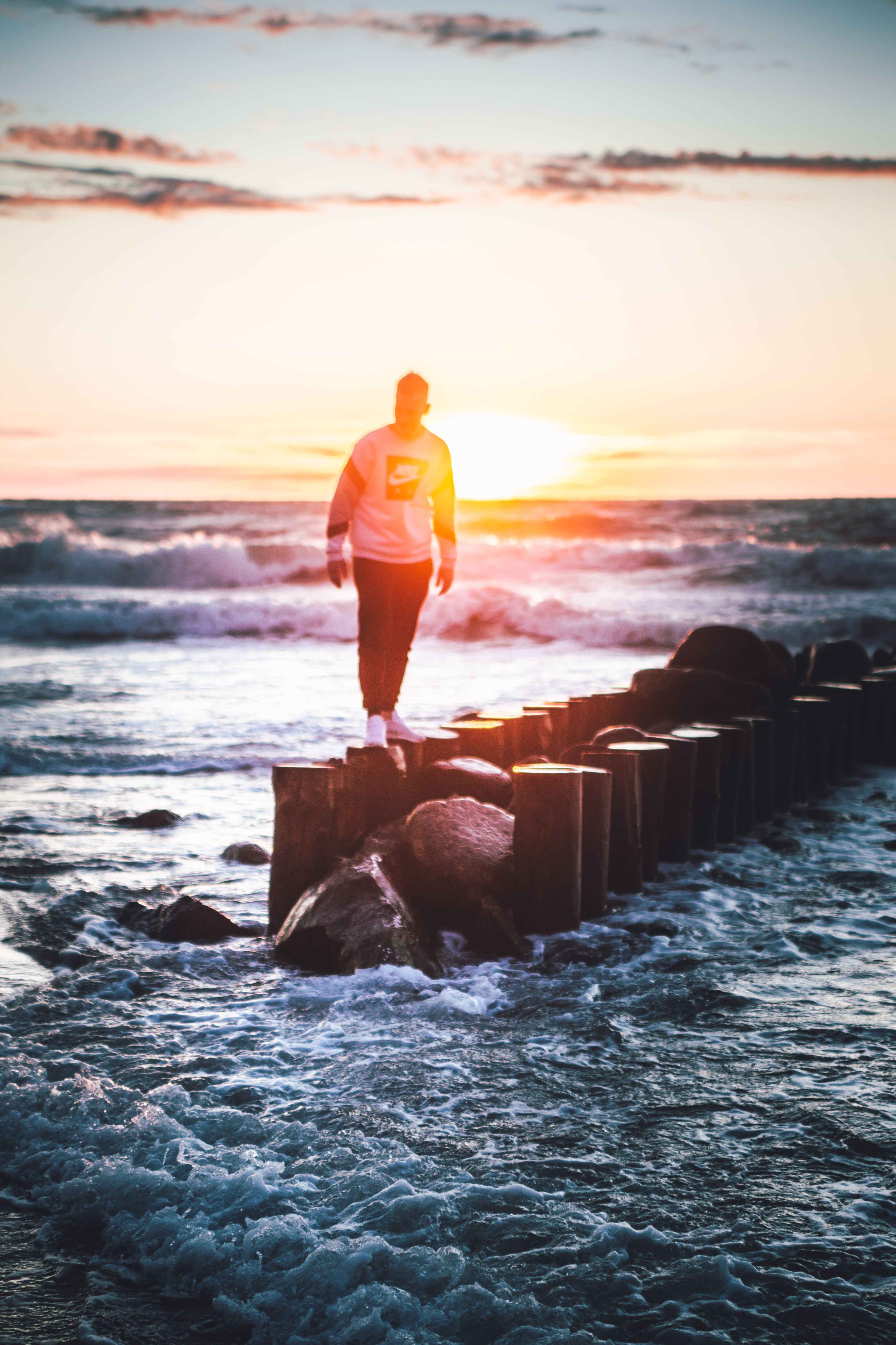 Man Standing on Wooden Breakwater at Sunset · Free Stock Photo