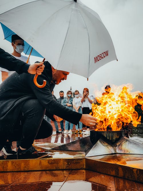 Foto profissional grátis de agachado, alcançando, chama