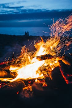 海滩上的篝火，在暮色的天空下，火花飞溅，营造出温暖而宁静的气氛