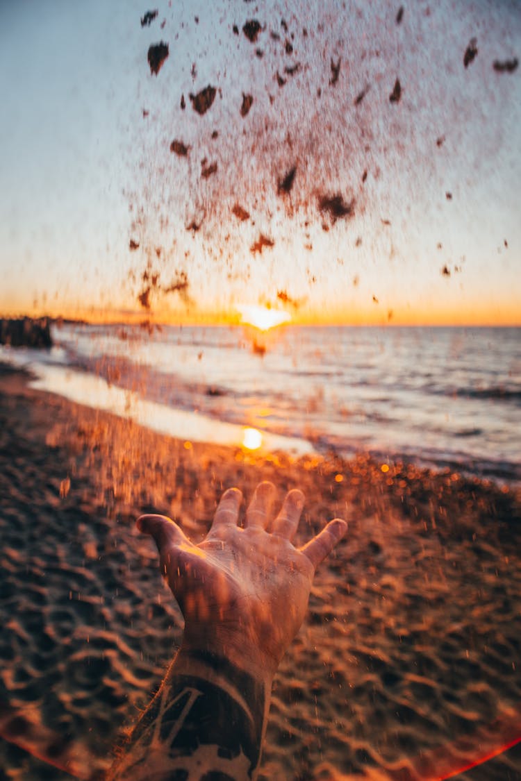 Hand Throwing Sand Into Air