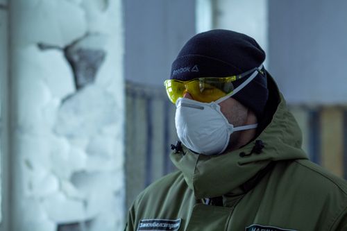 Free Man wearing safety glasses and mask indoors, emphasizing health and safety measures. Stock Photo