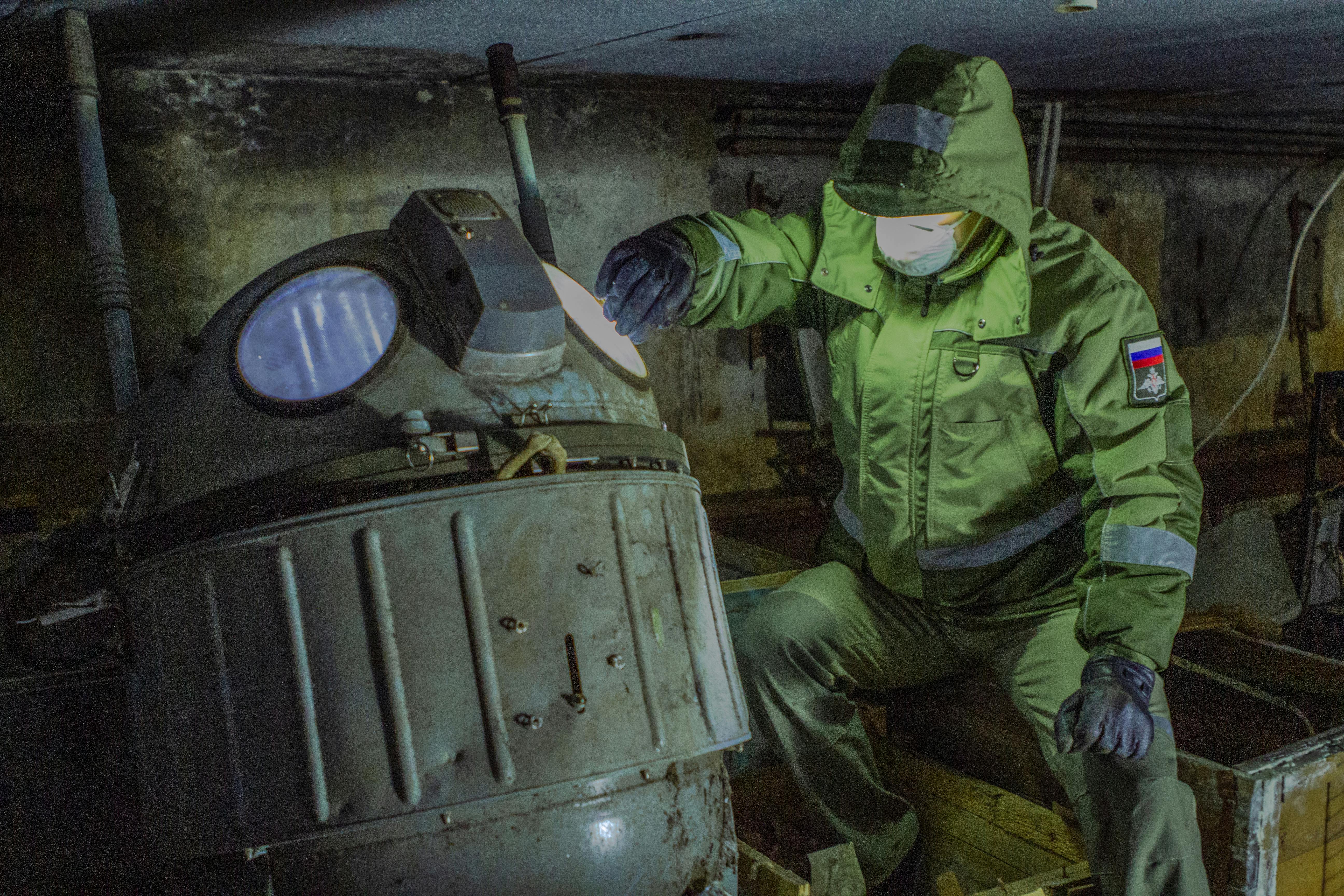 Industrial worker in protective gear inspects machinery indoors, highlighting safety and maintenance.