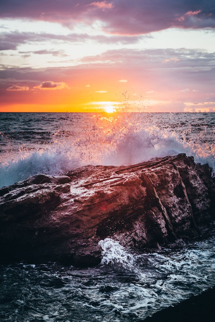 Waves Breaking On A Large Rock On The Coast At Sunset 