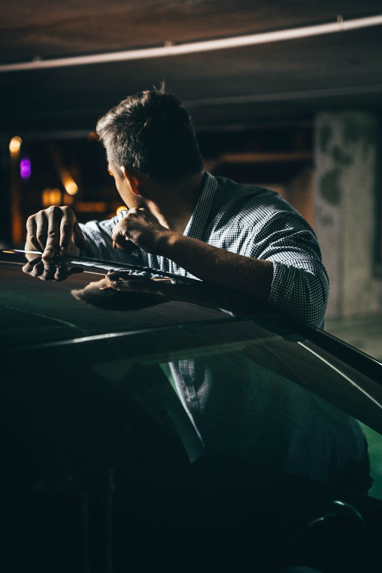 Dark Photo Of A Man Leaning Against A Car In A Garage