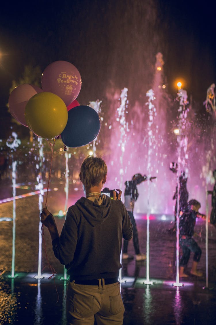 A Man Holding A Bunch Of Balloons