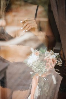An ethereal bridal moment captured through a window, featuring elegant lingerie and a romantic bouquet.